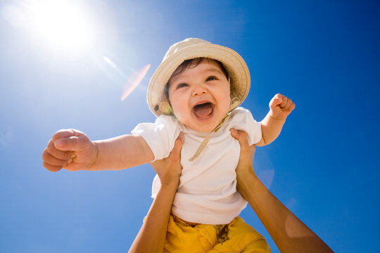 Hands holding baby (6-9 months) into air, portrait