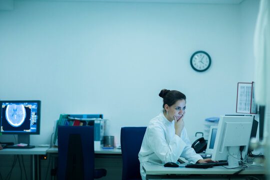 Young doctor in hospital looking at computer screen