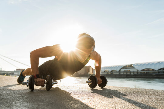 Fit athlete doing push ups at the river