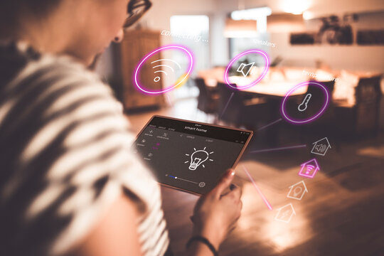 Woman sitting at home, using digital tablet to remote-control his smart home