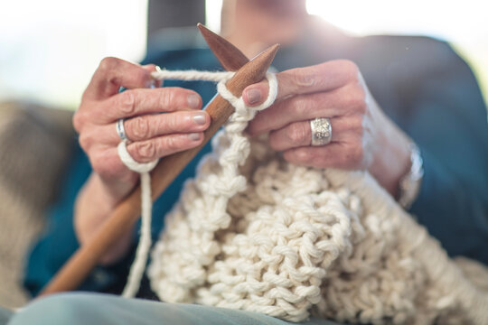Senior woman knitting on couch at home