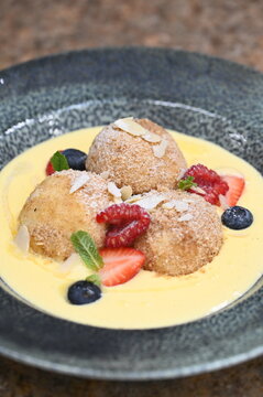 Traditional Czech fruit dumplings with fresh fruit, breadcrumbs, and vanilla sauce. Close-up of sweet homemade dessert, perfect for Czech cuisine
