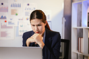 Stressed businesswoman suffering from headache and fatigue while working overtime at night in...