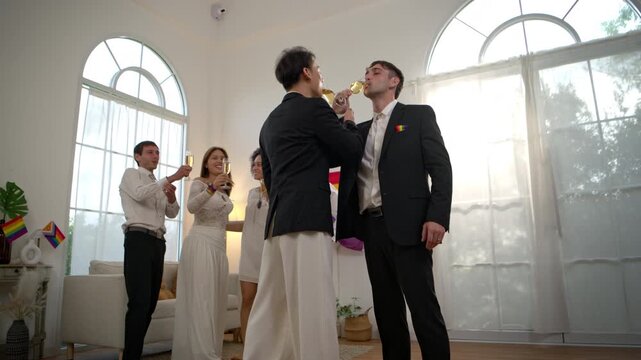 Same sex couple talking and celebrating with champagne during an LGBTQ Pride gathering with friends at home