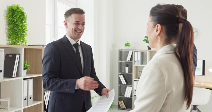 Businessmen and businesswoman handshake during office meeting. Smiling partners confirm agreement in a bright office, signaling trust and future cooperation. Symbol of clear business success.