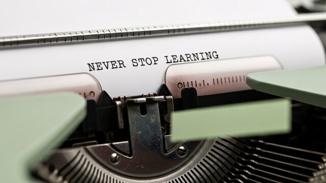 Close-up of a vintage typewriter with the phrase NEVER STOP LEARNING typed on the paper emphasizing continuous education and personal growth in a professional setting