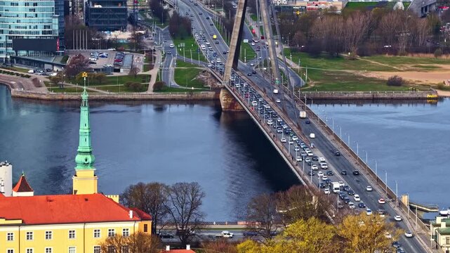 Aerial view of traffic crossing the Vansu Bridge over the Daugava River in Riga, Europe with historic rooftops and urban waterfront visible in Latvia&rsquo;s capital.