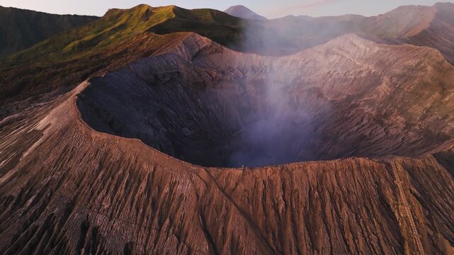 Mount Bromo volcano emit sulfurous fumes with tourists on crater rim, aerial