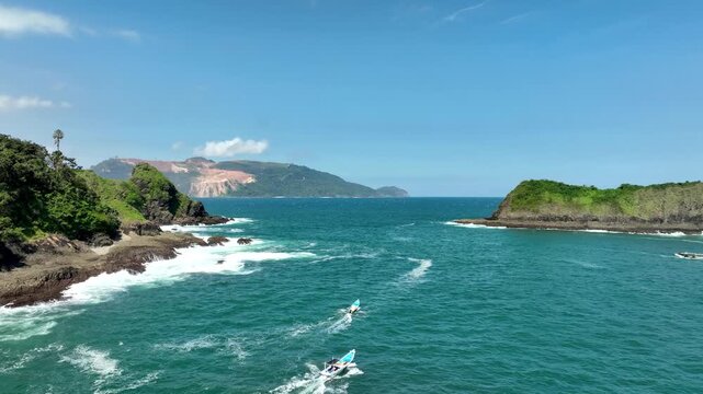 Aerial Pan of Motorboats Sailing Near Green Island Cliffs in Indonesia landscape