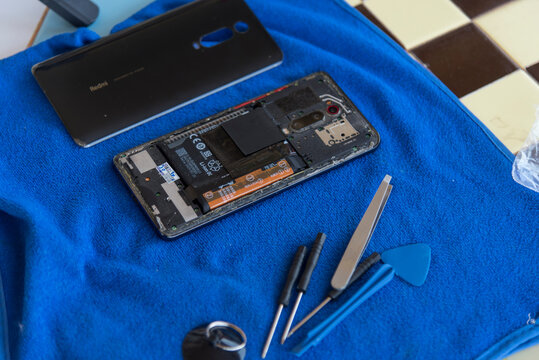 Nakhonpathom,Thailand - 20 March, 2026: Replacing old battery with Leeplus battery in Redmi K20 Pro smartphone on a repair desk.