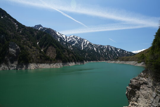 Emerald green water of Lake Kurobe with snowy alpine mountains.
