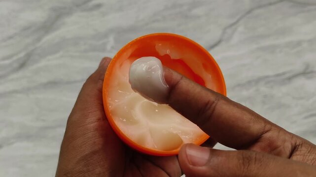 Closeup of finger scoop cosmetic skincare cream from plastic container. Toxic microplastic or nanoplastic particle fragments contamination in skin care and lifestyle beauty products concept.