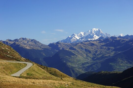 The pass road leading up to Col de la Madeleine, the snow-capped peaks of the Mont Blanc Massif at the back, Alps, France