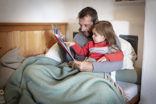 Father reading aloud with daughter, Bavaria, Germany
