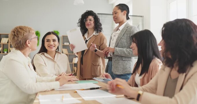 Women team meeting in office for strategy discussion. Collaboration and planning guide leadership with valued diversity. A diverse team reviews documents. Teamwork and leadership drive success.