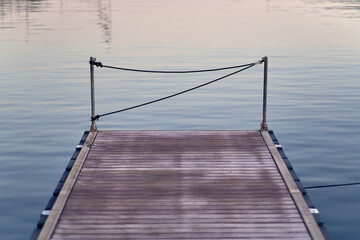 Fototapeta premium Wooden pier extending into calm reflecting water