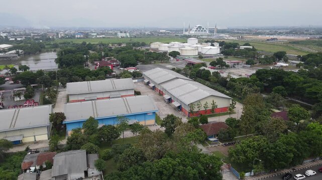 Aerial view of modern warehouse complex and industrial storage tanks in manufacturing district