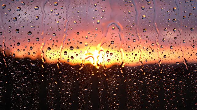 Golden sunset horizon seen through raindrops on window pane
