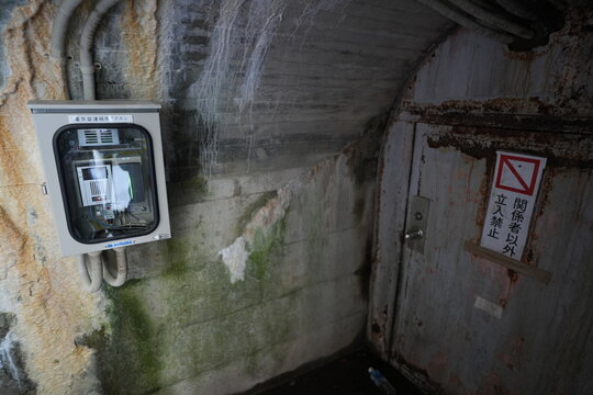 Restricted rusty door and control box in concrete tunnel.