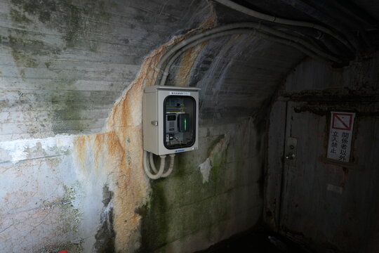 Restricted rusty door and control box in concrete tunnel.