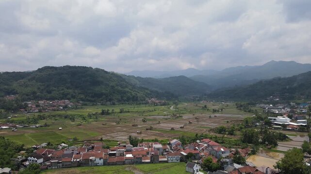Beautiful aerial view of green rice fields and rural village surrounded by mountains