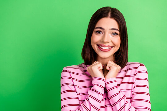 Young chic woman smiles in pink striped shirt against bright green background