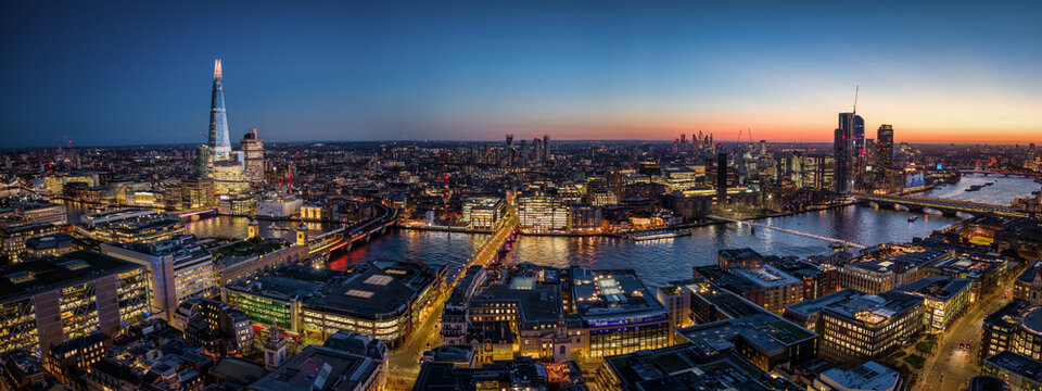 Panoramic aerial view of the skyline of London, England, stretching from London Bridge along the river Thames to Waterloo Bridge during dusk