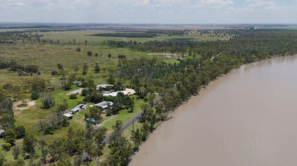 Fototapeta premium Scenic Aerial View of a Riverbank with Houses and Agricultural Land