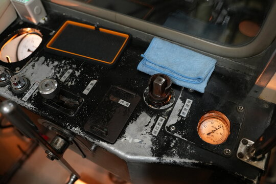 Vintage train control panel with mechanical levers and pressure gauge.