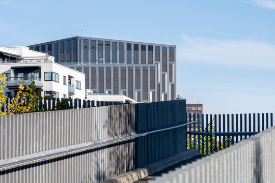 office building rises behind terrace railing and blue sky, where modern facade, urban architecture and balcony lines define a corporate exterior