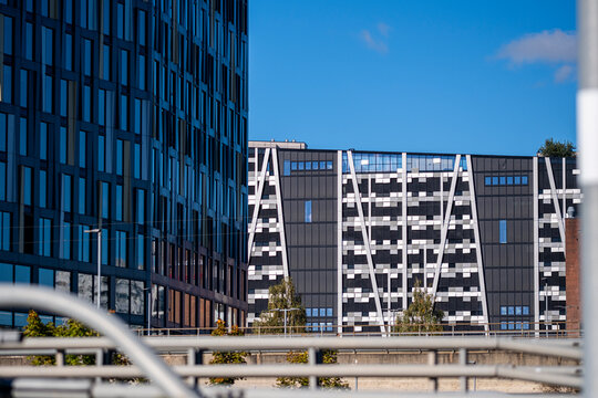 glass office towers align beyond railing and street structures, with corporate facade, blue sky and urban architecture layered in depth