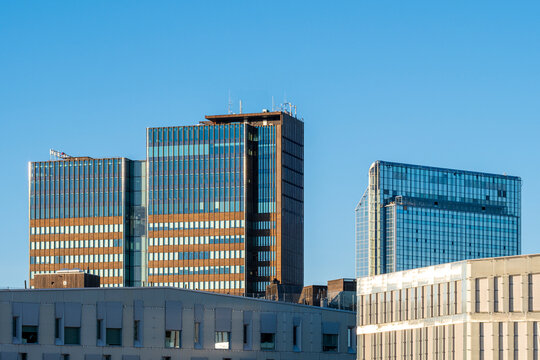 corporate towers stand above white rooftop edges, where glass facade, office skyline and blue sky shape a clean urban architecture scene