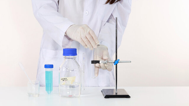Scientist in Lab Coat Handling Test Tube with NaOH Solution Experiment