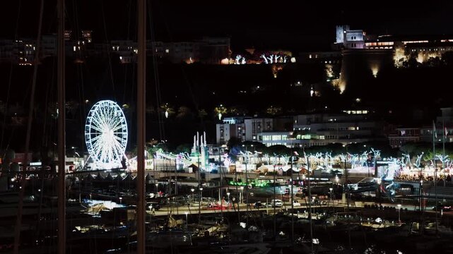 Night aerial view of Monaco Christmas market with ferris wheel and festive lights at Port Hercule.
