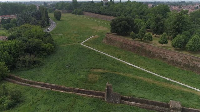 Aerial view of the ancient city walls and green fortifications with walking paths and lush trees in Ferrara, Emilia-Romagna, Italy.