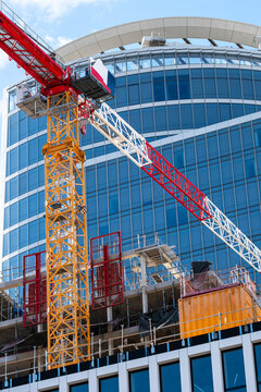 beside a glass building facade, a construction crane marks an urban site as city development and architecture rise into open sky above windows