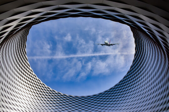 Basel, Switzerland. The Exhibition center.
The circular hole in the abstract roof construction of the Basel Exhibition Centre. A passenger plane flying over the city. Sky blue.
