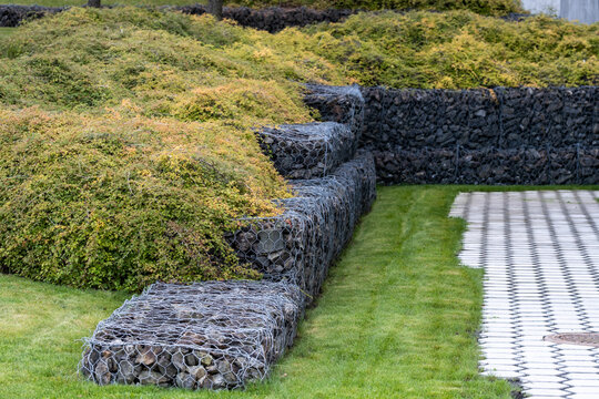 garden lawn curves beside stone wall seating in an urban landscape, where architecture, green terrace and pathway define a quiet exterior