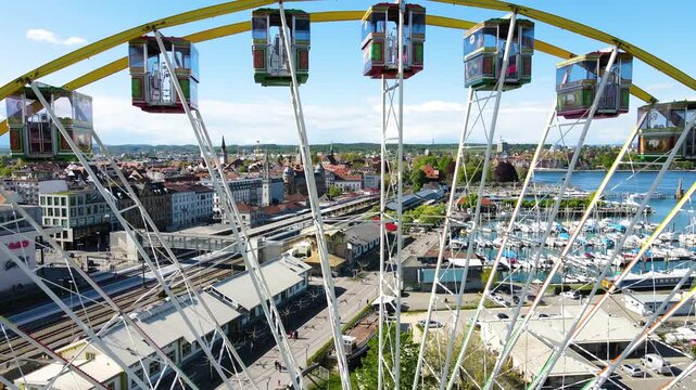 Close aerial pass by ferris wheel framing Konstanz cathedral