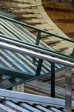 glass roof and metal railings overlap beneath warm wooden ceiling, where urban architecture turns exterior stairs into layered transparent geometry