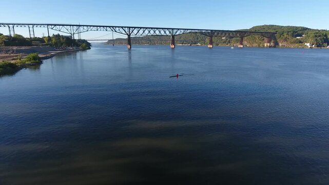 Aerial view of the Hudson River with a rower on the water and the historic bridge spanning the banks in Poughkeepsie, New York, United States.
