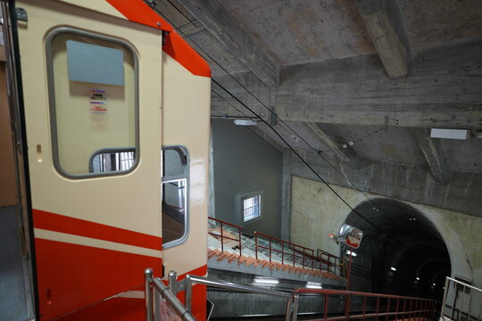 An orange alpine cable car parked at underground station platform.