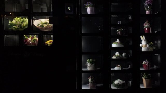 Flower vending machine at night. Fresh bouquets, cemetery floral arrangements, potted flowers and variety of gifts in a dispensing machine. Innovative 0-24 shopping concept. Tilt up slow motion.