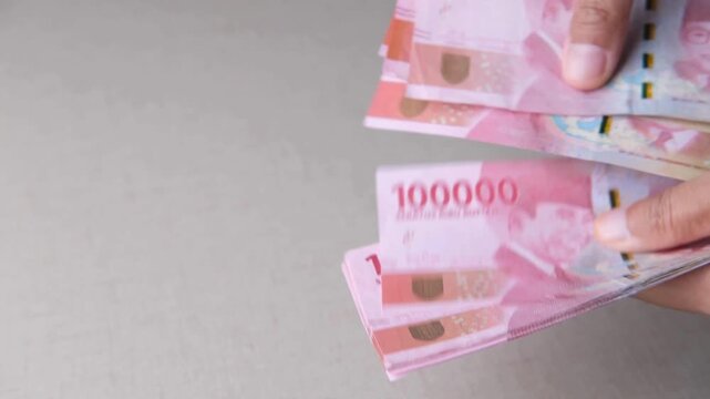 Hand holding Indonesian rupiah bills.