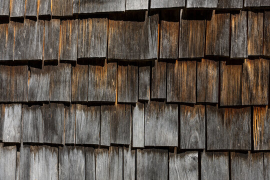 Weathered wooden shingles on traditional alpine chalet facade, rustic Bavarian architecture texture for construction, renovation and travel backgrounds