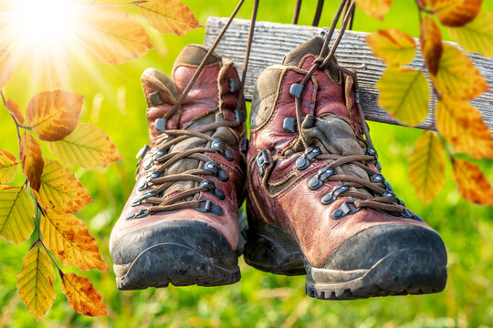 Ein Paar Wanderstiefel aus Leder h&auml;ngen mit Herbstlaub an einem h&ouml;lzernen Zaun  im Allg&auml;u - FOTOMONTAGE