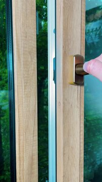 Hand opens window sash beside mosquito screen indoors. Concept of ventilation, fresh airflow and comfortable residential living.