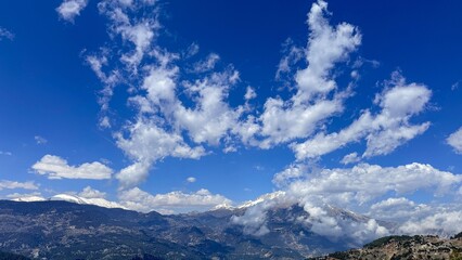 Wide mountain range under vivid blue sky with scattered white clouds, distant peaks and valleys create a calm expansive mood, ideal for travel and nature themes © fotoworld