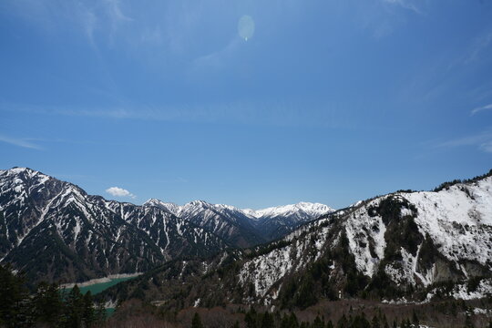 Panoramic view of snowy Japanese Alps and emerald Kurobe Lake.