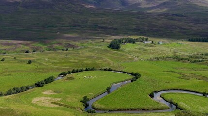 Fototapeta premium Aerial View of a Winding River Through Lush Highland Meadows